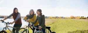 Family of women on bikes near a lake