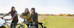 Family of 3 women on bikes near a lake